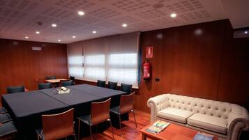 A conference room with a large table, chairs, a sofa, and a fire extinguisher.