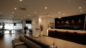 A modern hotel lobby with a reception desk, seating area, and a large window providing natural light. - Hotel Europa (Utebo)