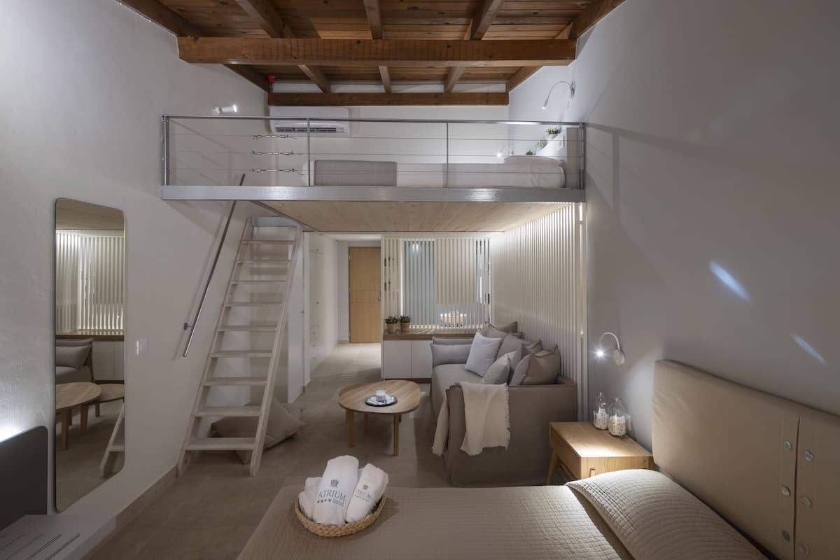 A modern loft bedroom with a loft bed, a sofa, a small table, and a staircase.