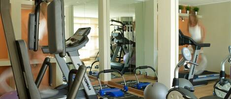 A home gym with exercise equipment, including a treadmill, stationary bike, and weights.