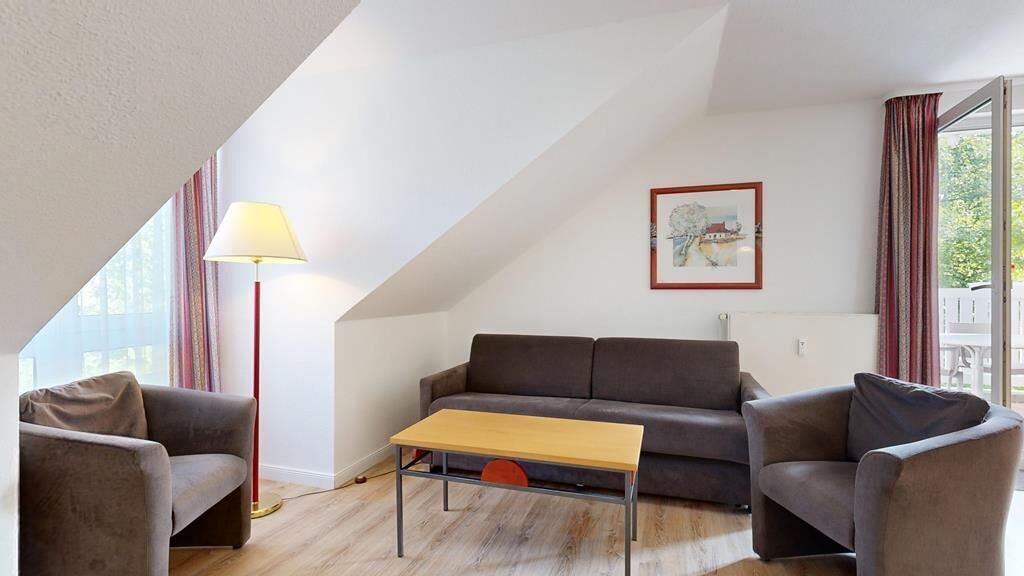 Un salon comprenant un canapé, deux fauteuils, une table basse, un lampadaire et un tableau encadré accroché au mur.