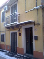 Un edificio amarillo con un balcón, una puerta y una ventana.