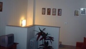 A living room with a television, a plant, and framed pictures on the wall. - Don Diego (Linguaglossa)