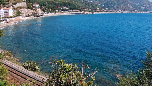 A coastal town with a clear blue sea, a beach, and buildings along the shore. - Don Diego (Linguaglossa)