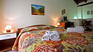 A hotel room with a bed, two bedside lamps, a desk, a chair, and a painting on the wall. - Don Diego (Linguaglossa)