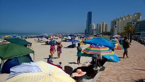 A beach with umbrellas and people.