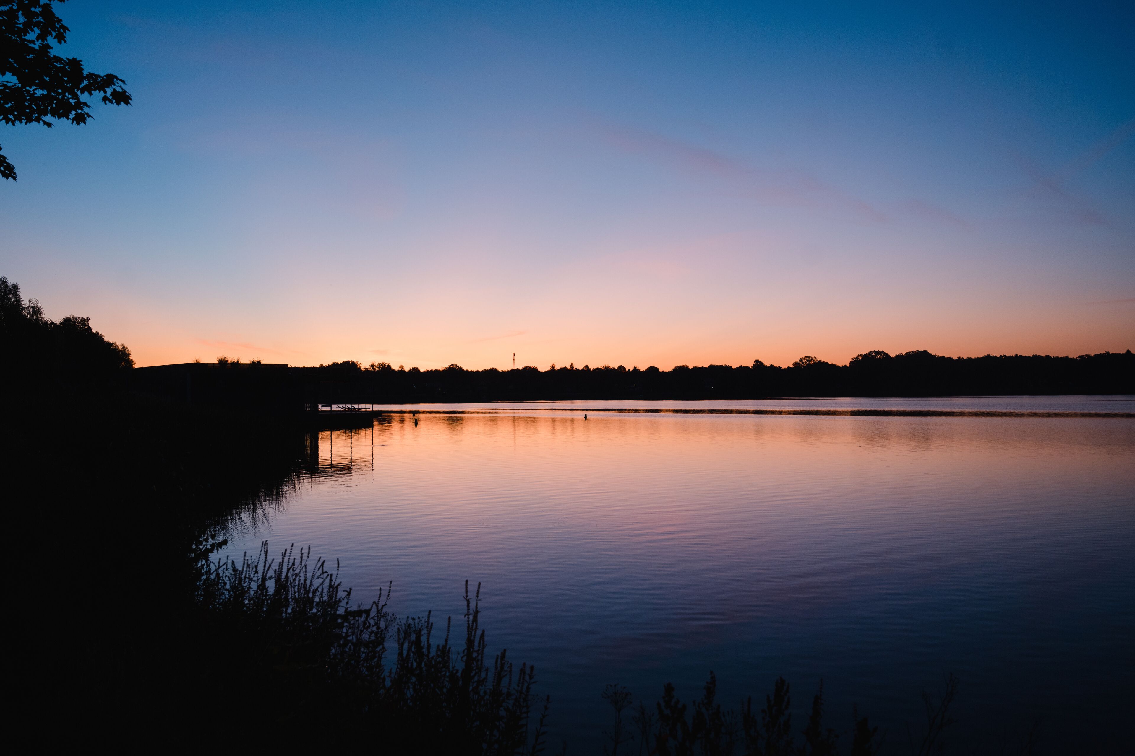 A calm lake at dusk with a clear sky.