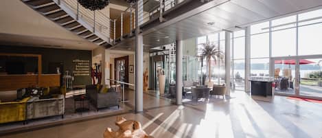 A spacious lobby with a staircase, seating area, and large windows offering views.