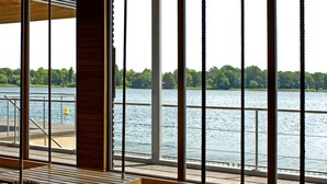 Een houten terras met banken met uitzicht op een wateroppervlak.