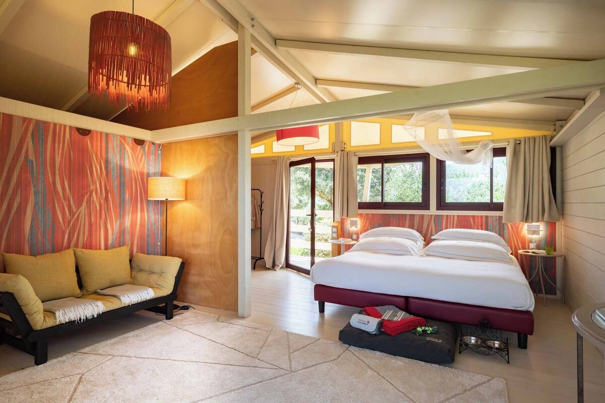 A spacious bedroom with a large bed, a sofa, and a dining table.