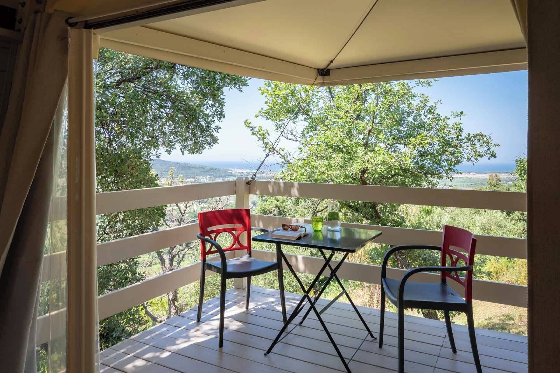 A balcony with a table and two chairs, overlooking a scenic landscape.