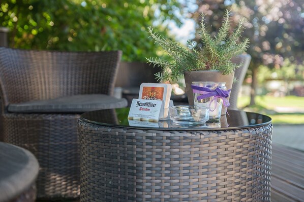A wicker table with a glass, a candle, and a card on it.