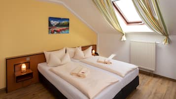Un dormitorio con dos camas, un cuadro en la pared, un tragaluz y una ventana con cortinas.