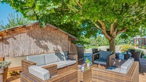 Een terras met wicker meubilair en een houten terras.