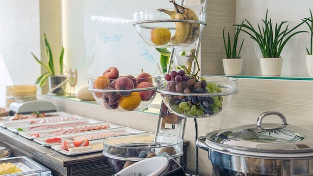 Een buffet met diverse soorten fruit, gebak en drankjes.