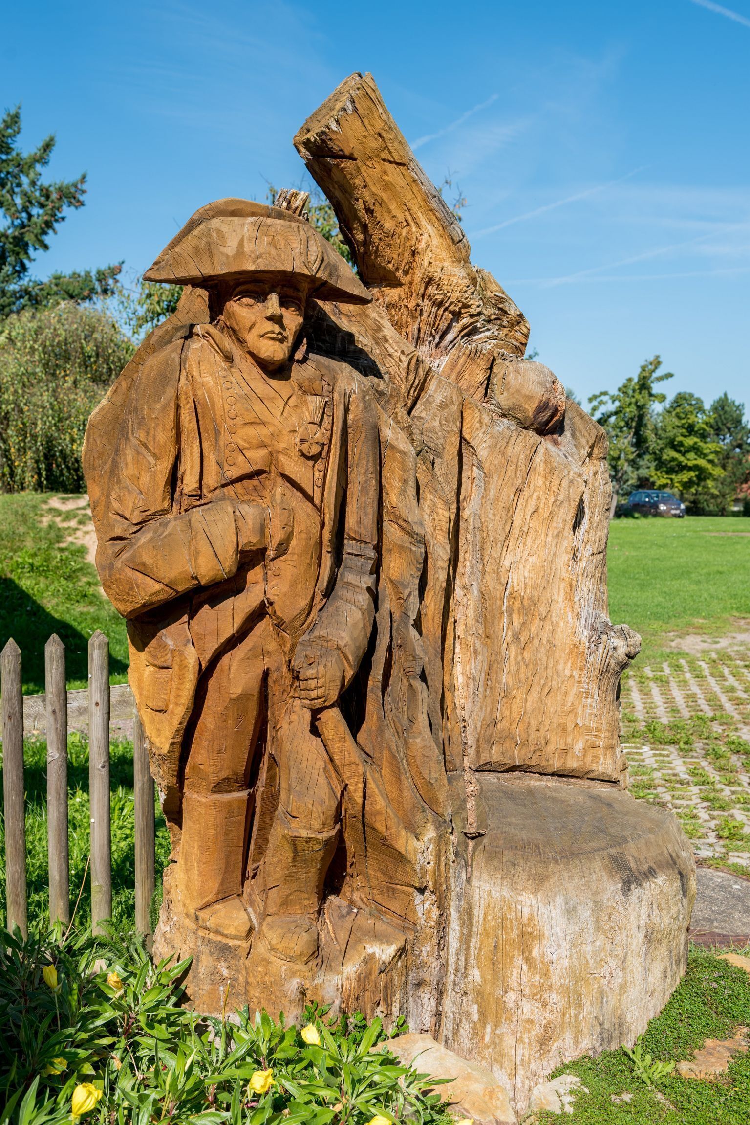 Una escultura de madera de una figura histórica en un parque.