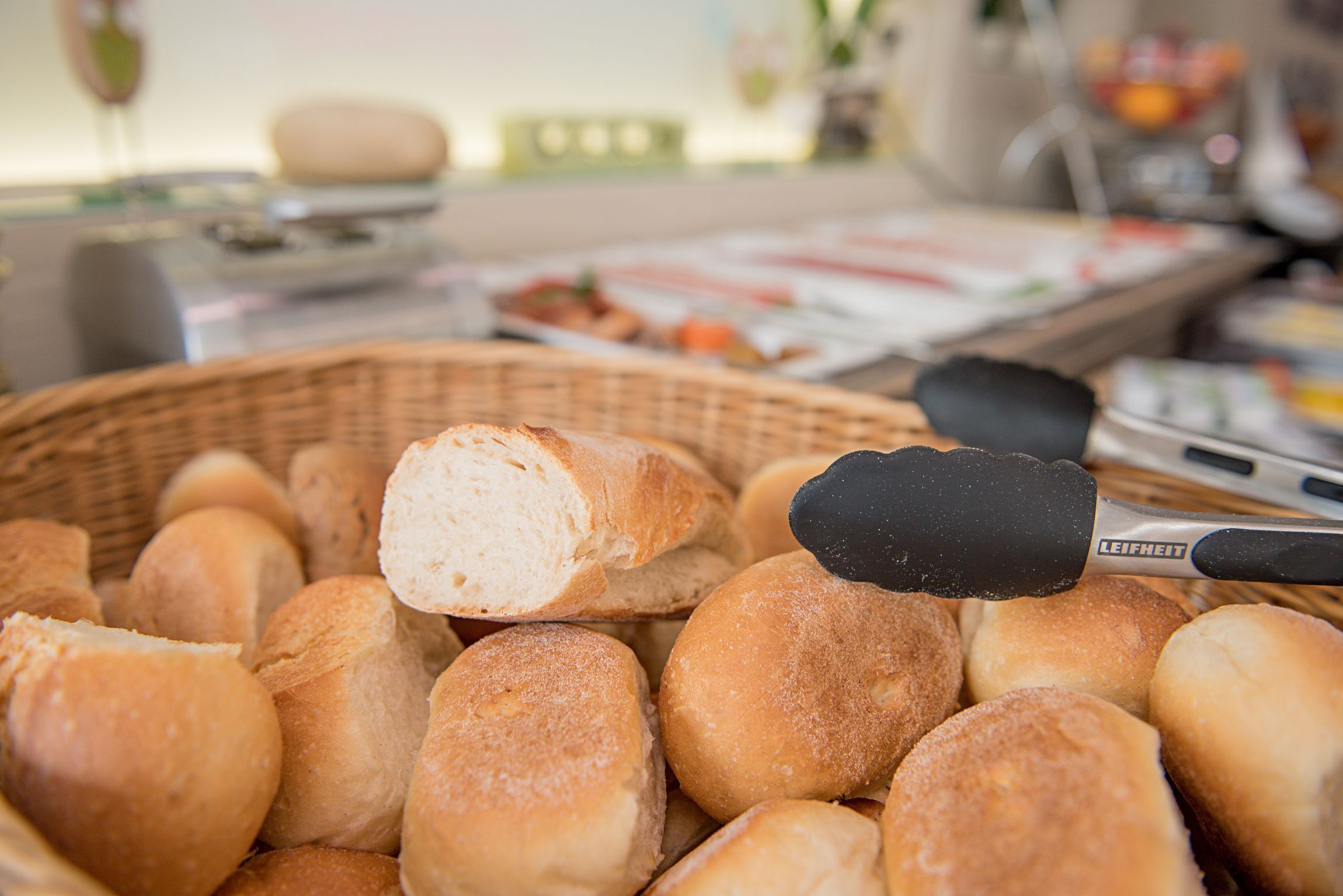 Ein Korb mit frisch gebackenen Brötchen, einem Nudelholz und einer Butterpackung.