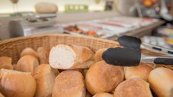 Ein Korb mit frisch gebackenen Brötchen, einem Nudelholz und einer Butterpackung.