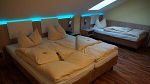 A spacious attic bedroom with a large bed, two bedside tables, and a skylight. - Kleindienst (Ursensollen)