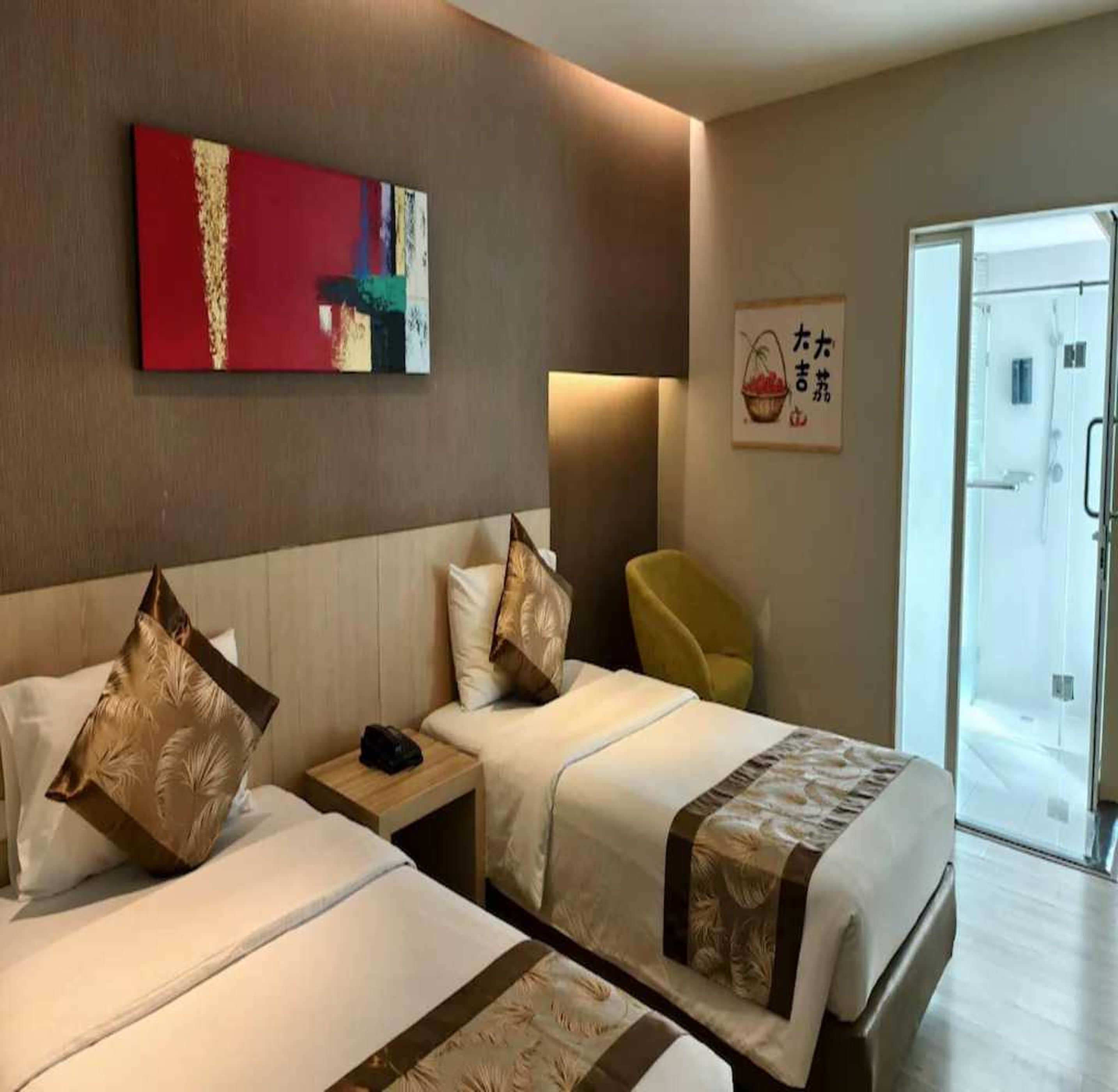 A hotel room with two beds, a nightstand, a chair, and a wall-mounted artwork.
