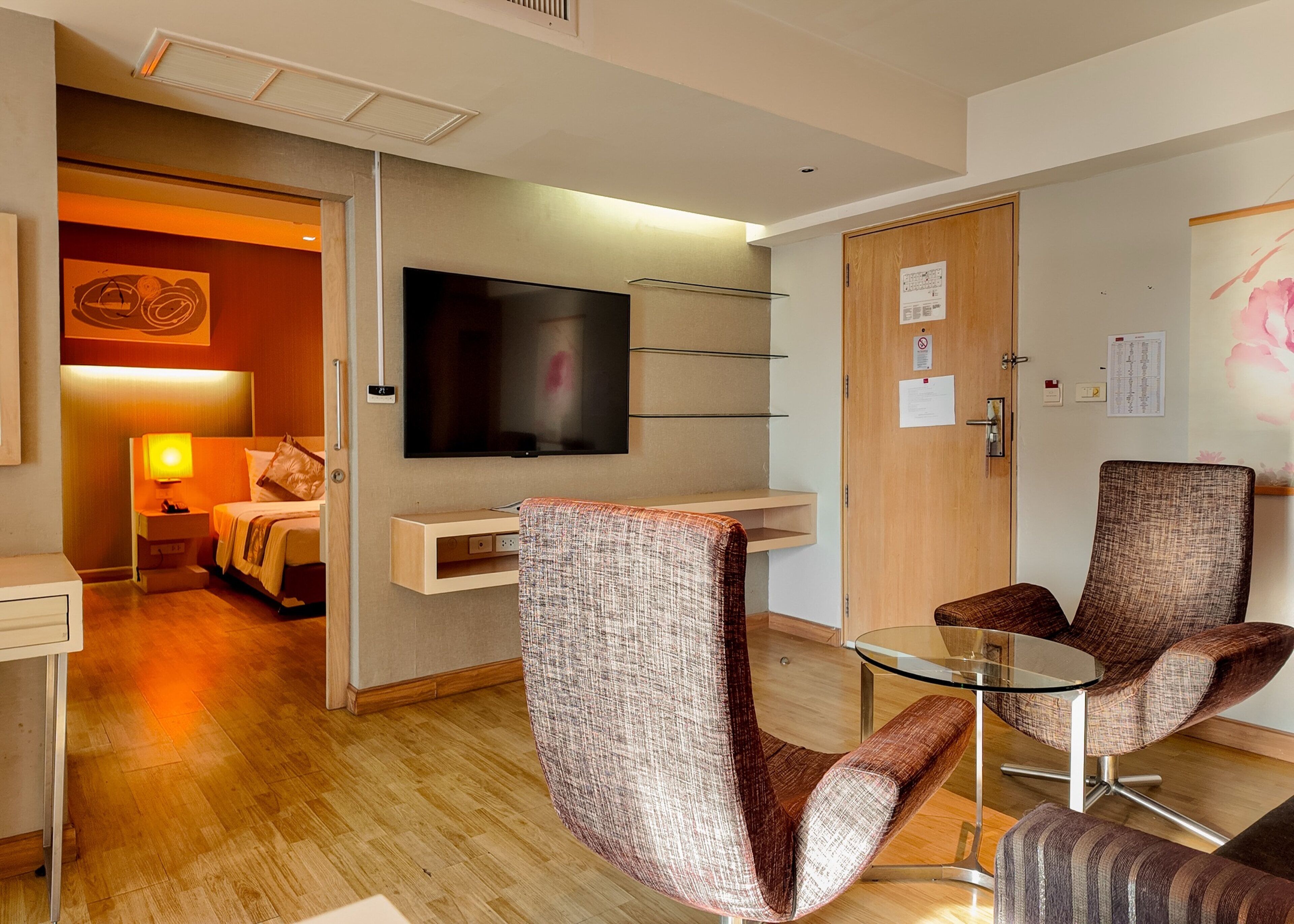 A hotel room with a bed, a TV, a desk, and two chairs.