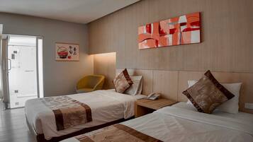 A hotel room with two beds, a chair, a bedside table with a phone, and artwork on the wall.