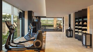 A modern gym with exercise equipment, a television, and a view of the outdoors. - Courtyard by Marriott Gurugram Downtown (Gurugram)