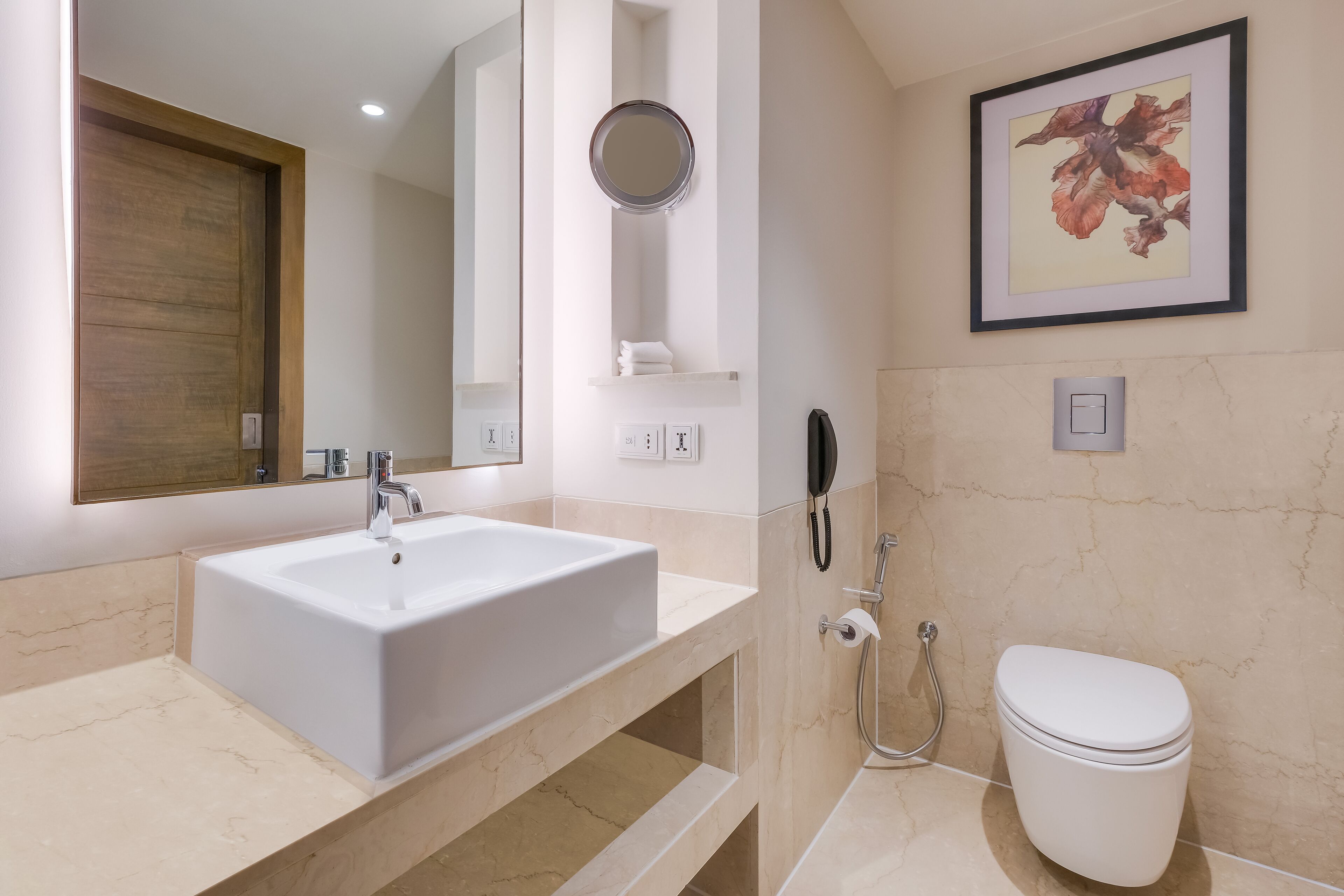 A modern bathroom with a large white sink, a mirror, a toilet, and a shower.