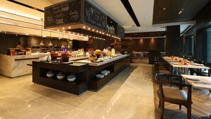A modern restaurant with a central island buffet, a chalkboard menu, and a clean, contemporary interior. - Courtyard by Marriott Gurugram Downtown (Gurugram)