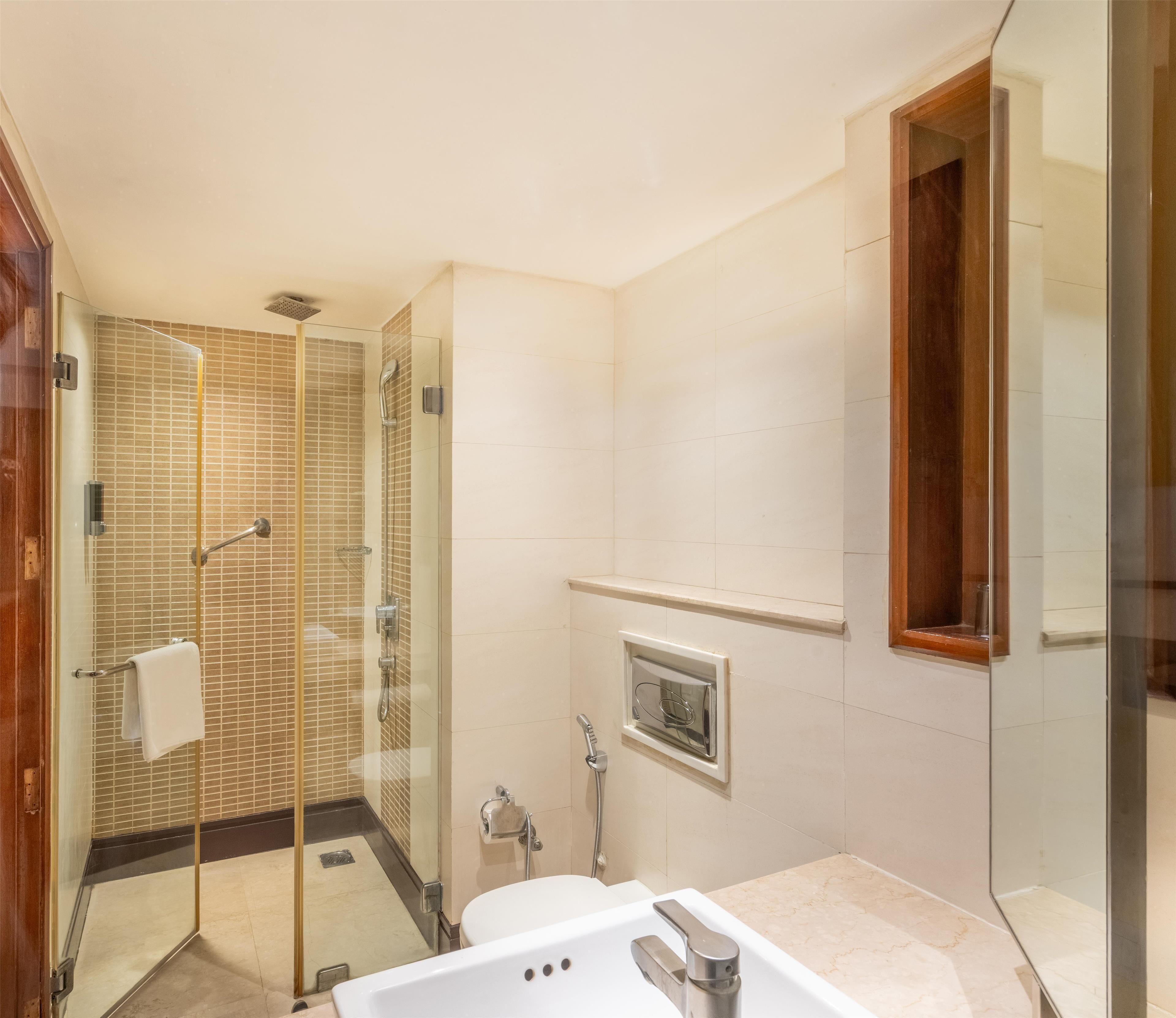 Une salle de bain moderne avec une douche à parois de verre, une baignoire blanche et un miroir encadré en bois.