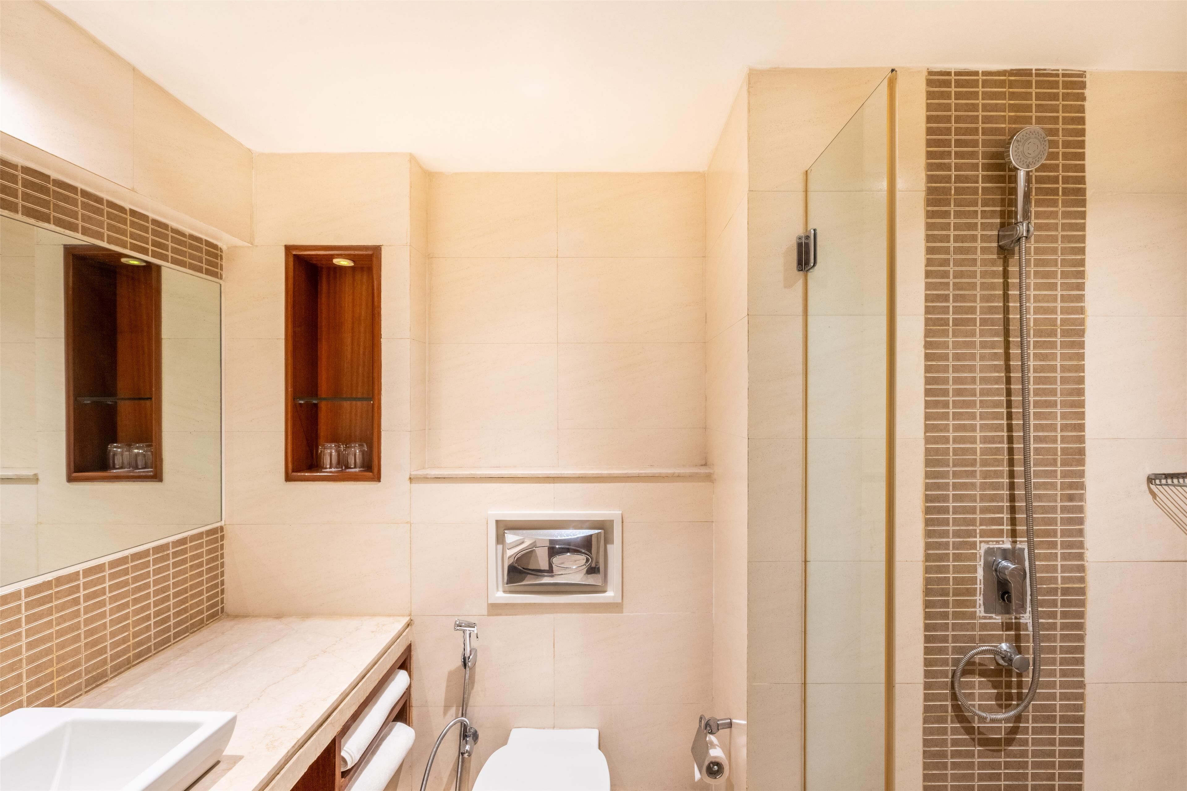 A modern bathroom with a glass-enclosed shower, a large mirror, and a vanity with a sink.