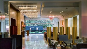 A spacious lobby with a reflective floor, modern chandeliers, and seating areas. - Park Inn, Gurgaon (Gurugram)