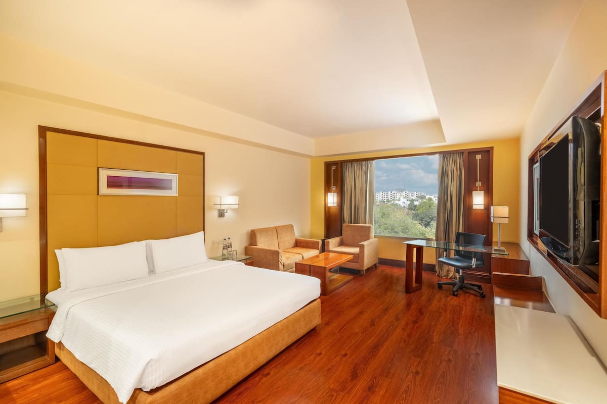 Een hotelkamer met een groot bed, een bureau, een stoel en een televisie.