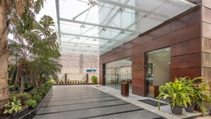 A modern hotel lobby with a glass ceiling, potted plants, and a 'Park Inn' sign. - Park Inn, Gurgaon (Gurugram)