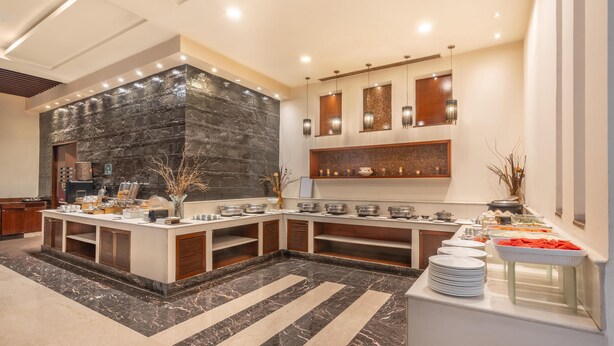 A modern kitchen with a marble countertop, built-in appliances, and a stone accent wall. - Park Inn, Gurgaon (Gurugram)
