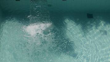 Alberca al aire libre, sombrillas en la alberca y camastros