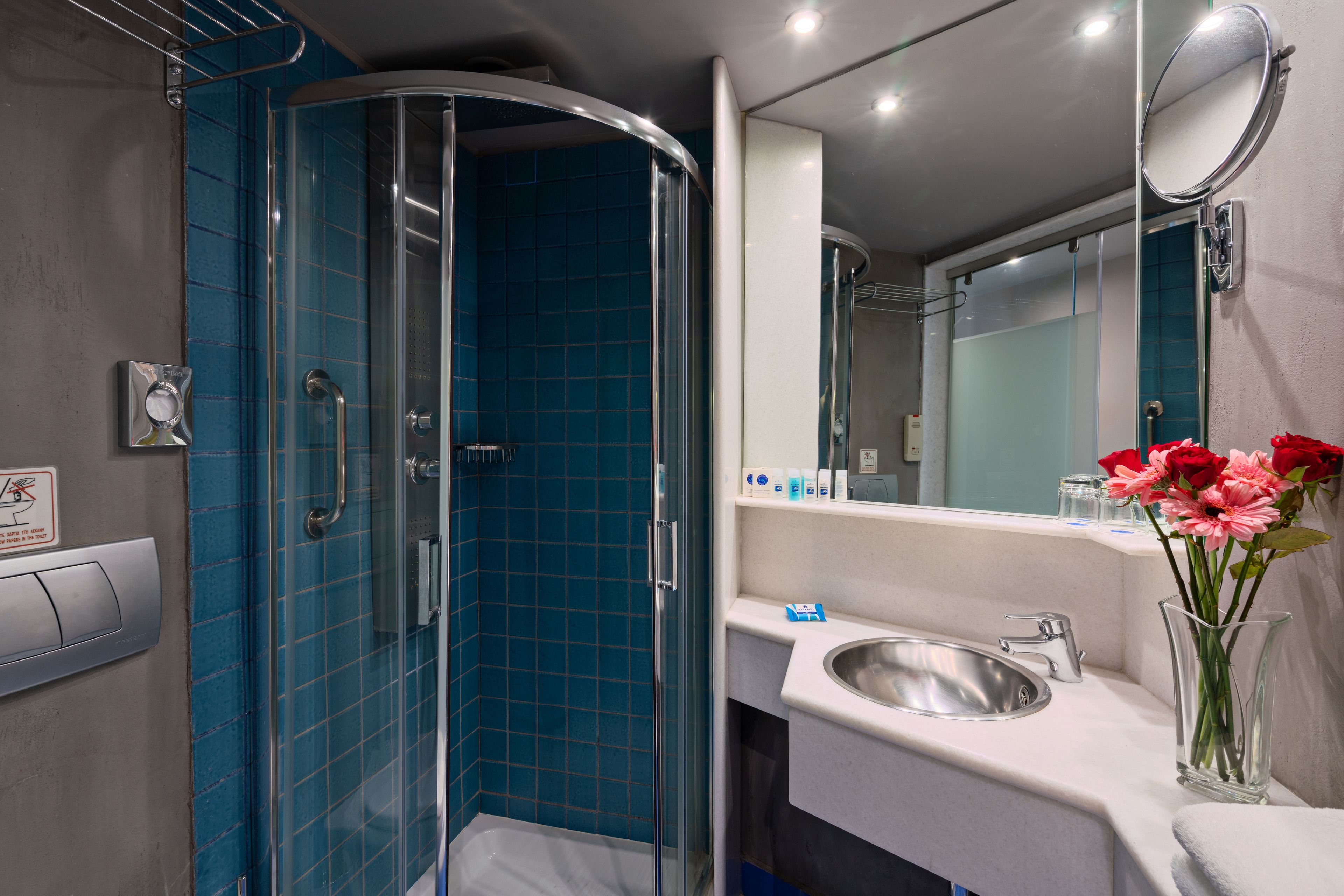A modern bathroom with a glass shower enclosure, a sink, and a mirror.
