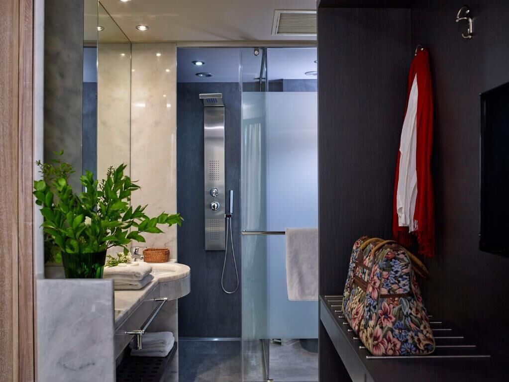 Un baño moderno con cabina de ducha de vidrio, lavamanos de mármol y toallero.