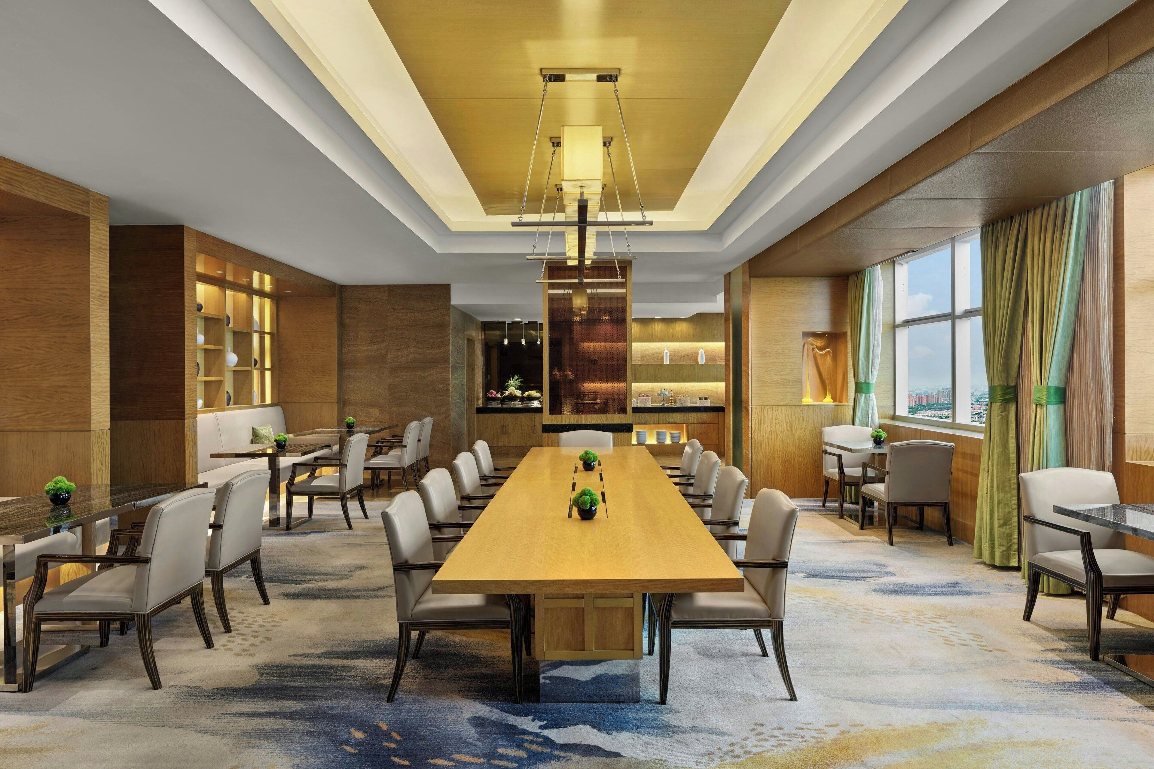 A spacious conference room with a long table, multiple chairs, and a modern chandelier.