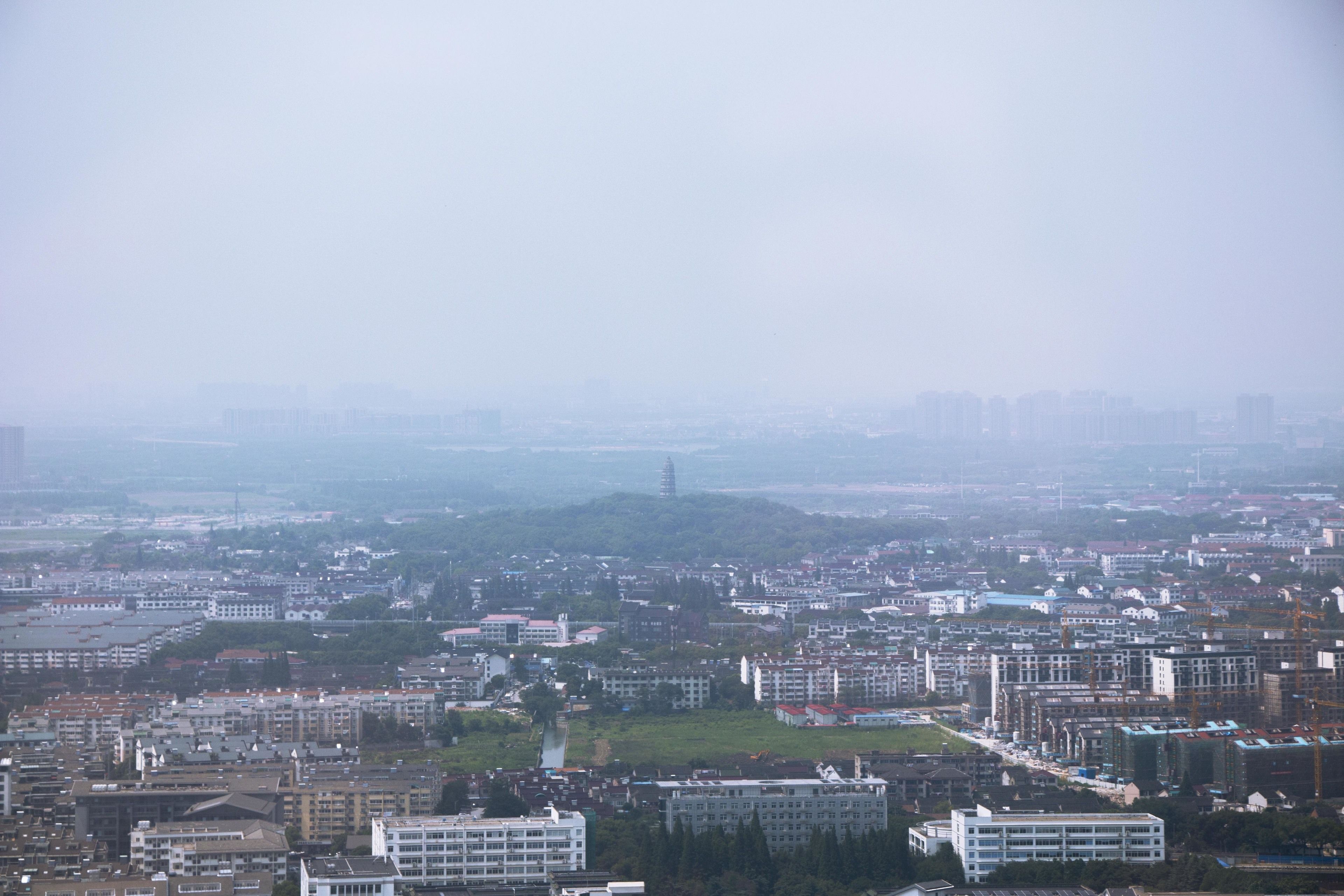 A cityscape with multiple buildings, including a prominent white building with a green roof in the foreground.