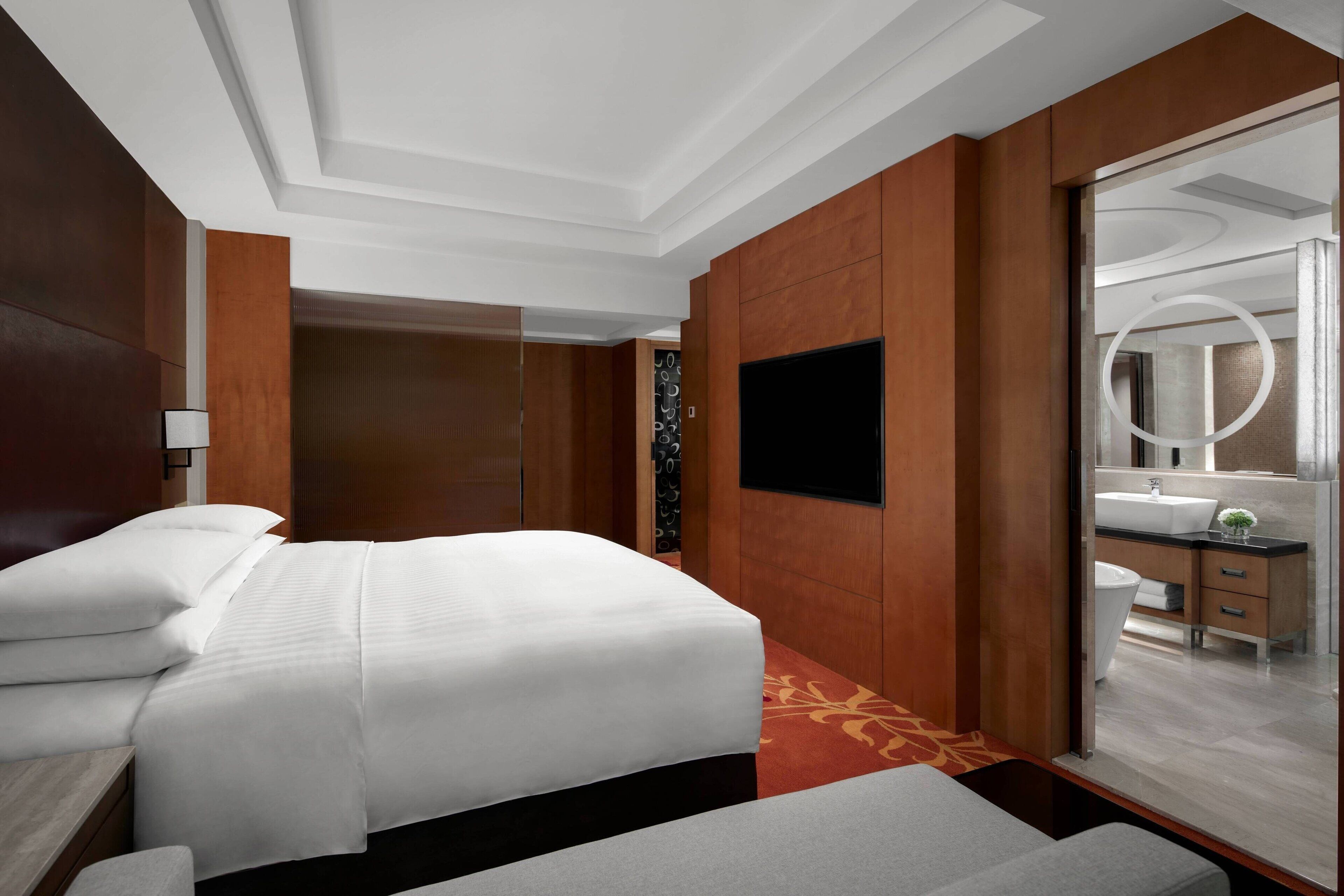 Une chambre d’hôtel avec un grand lit, une table de chevet, un miroir et une vue sur la salle de bain.