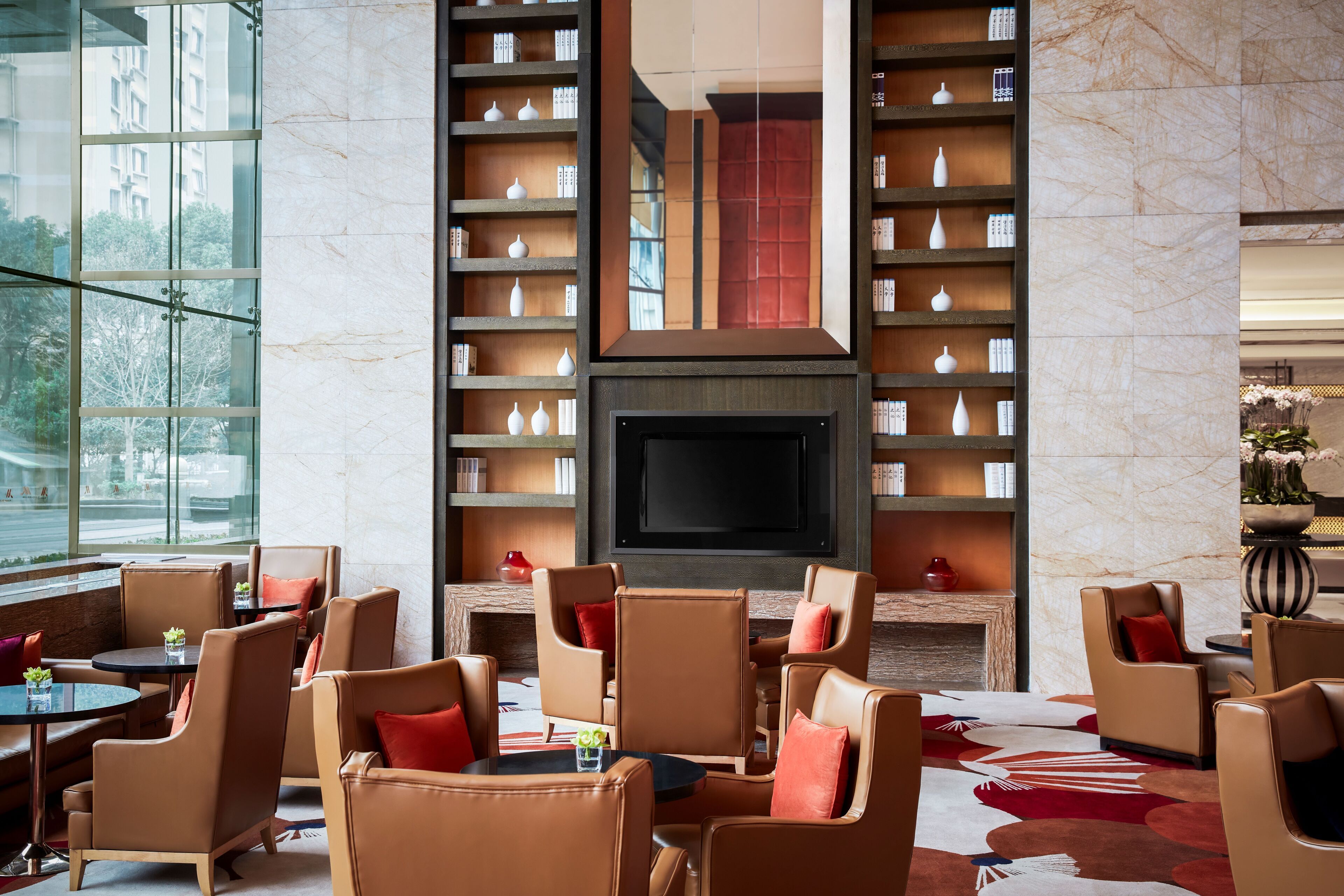 A modern interior with leather chairs, a fireplace, and bookshelves.