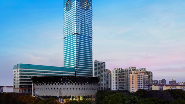 A tall, modern skyscraper with a distinctive clock tower and a unique, lattice-patterned structure at its base. - Suzhou Marriott Hotel (Suzhou)