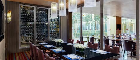 Un salón de conferencias con una larga mesa, sillas y una vinoteca al fondo.