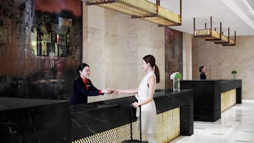 A reception area with a marble reception desk, a large abstract mural, and a patterned wall design.