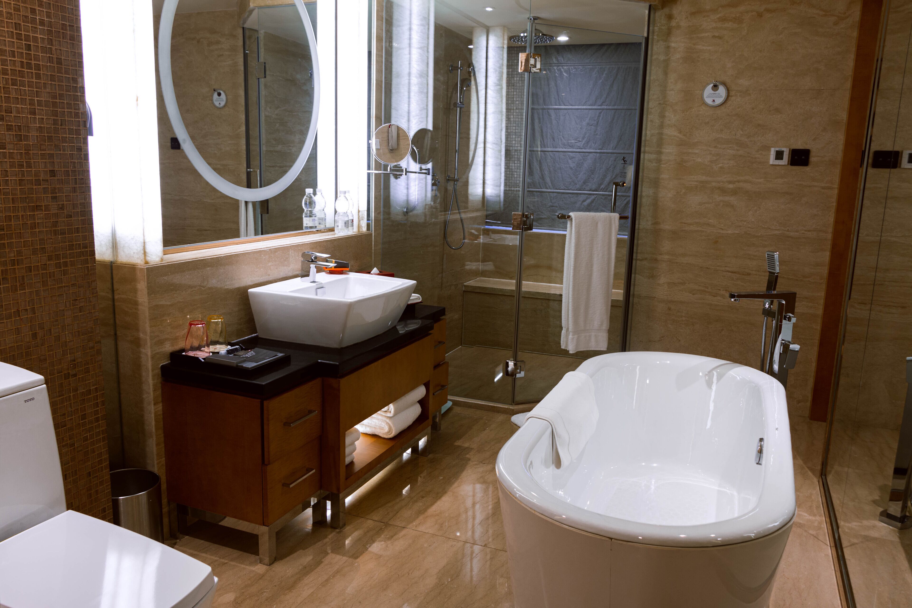 A modern bathroom with a large bathtub, a glass-enclosed shower, and a vanity with a sink and mirror.