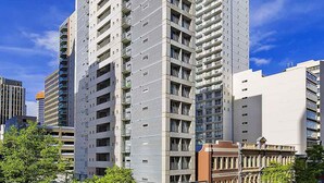 Un moderno hotel grattacielo con numerosi piani, balconi e cielo sereno.