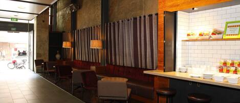 A restaurant with a bar area, seating, and a view of the street.