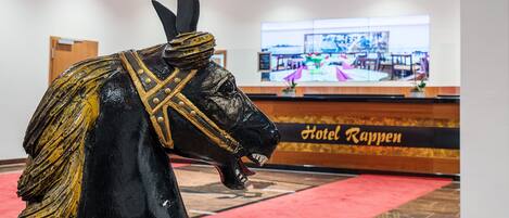 Une statue de cheval se trouve dans le hall d’entrée, près d’un comptoir de réception et d’un grand écran qui diffuse une vue du restaurant.