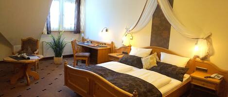 Une chambre d’hôtel avec un grand lit, un bureau, une chaise, une table de chevet et une plante en pot.